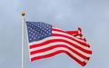 An american flag is waving in the wind on a pole.