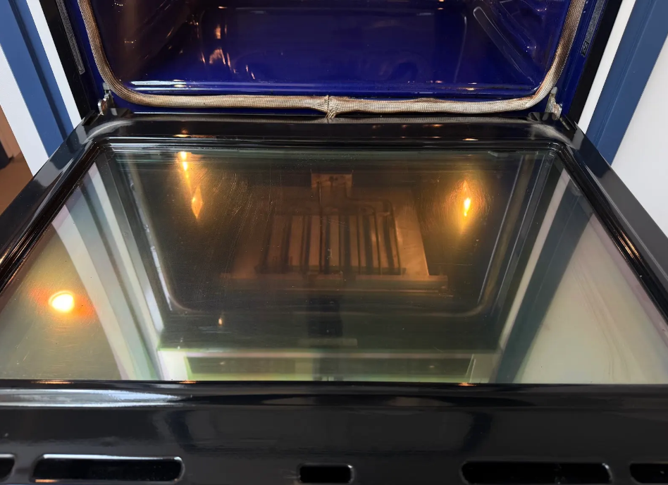 Open oven with reflective glass door and warm interior light
