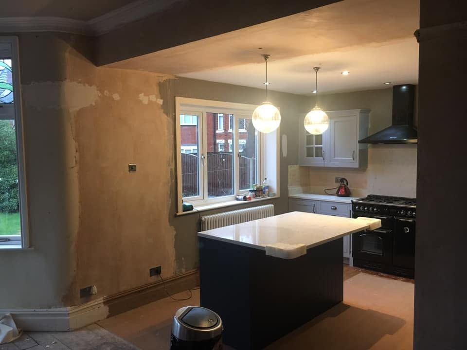 Kitchen under renovation with an island, pendant lights, and black appliances