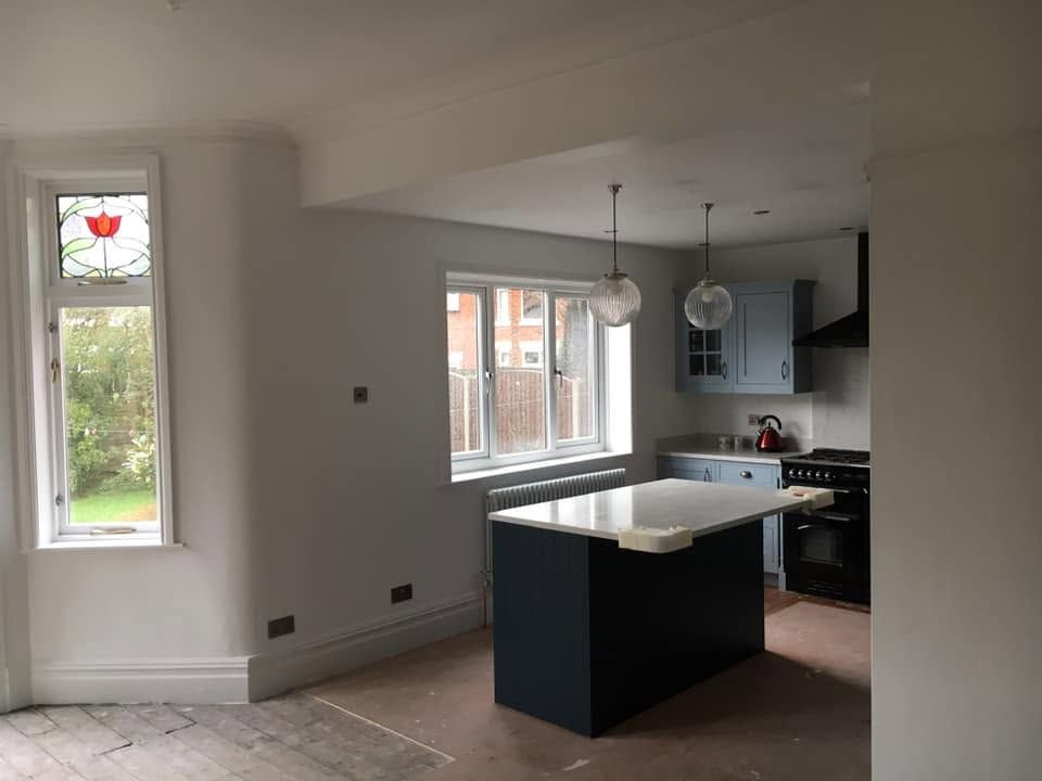 Modern kitchen with black island, white countertops, and large windows in a bright open-plan room