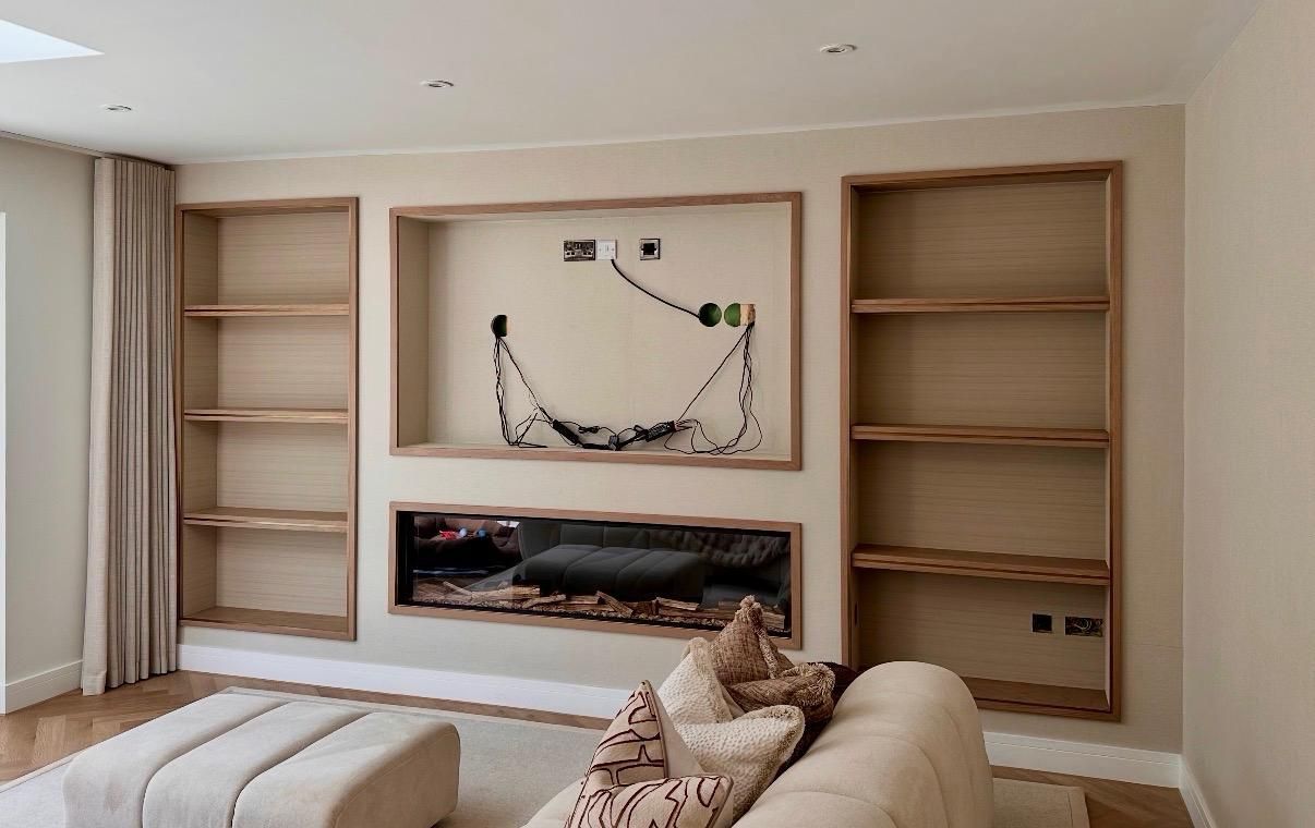 Modern living room with wall-mounted TV, built-in shelves, and a long linear fireplace on a dark feature wall.