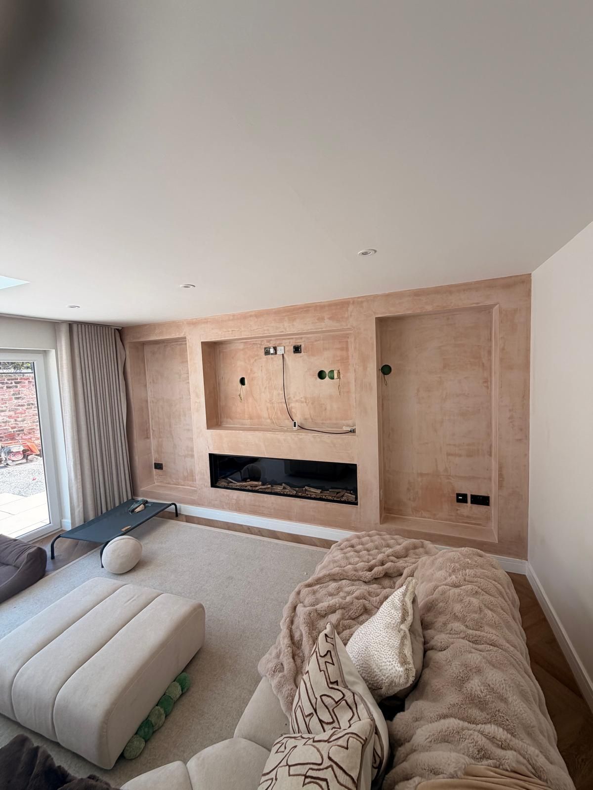 Modern living room with wall-mounted TV, dark media console, and plants by a bright window