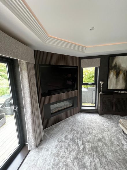 Modern living room with wall-mounted TV, dark vertical slat accent wall, and built-in shelving by a window