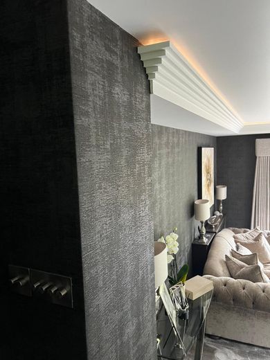Elegant living room with fireplace, wall-mounted TV, beige sofas, and tall green plants
