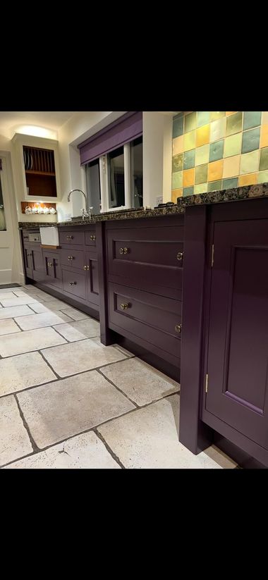 Dark green kitchen with white countertops, stainless appliances, and glass-front cabinets.