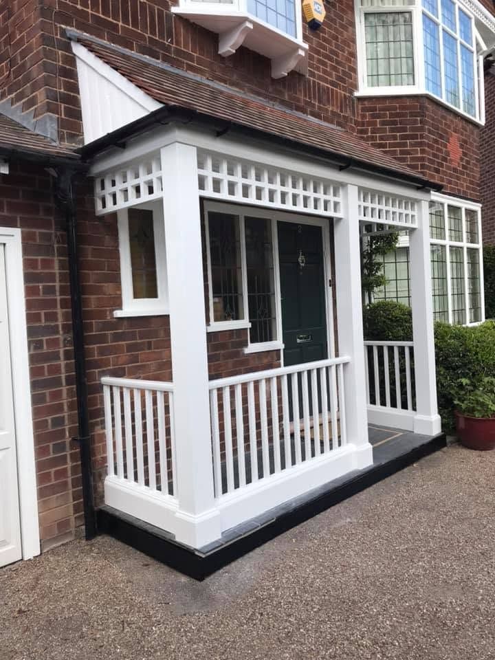 Front door of a brick house with black door, white trim, and a small doormat on the porch.