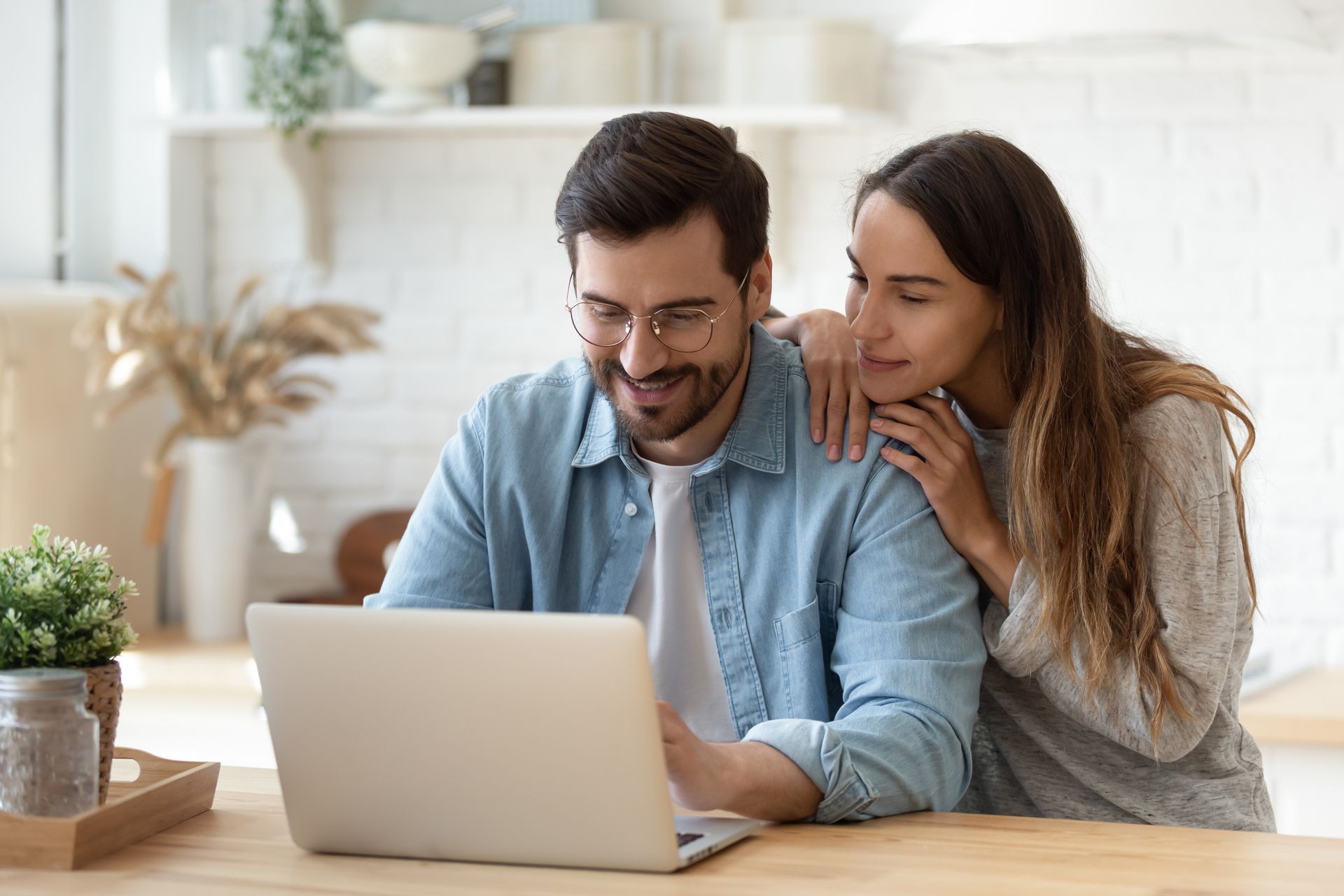 a man and a woman are sitting at a table looking at a laptop computer