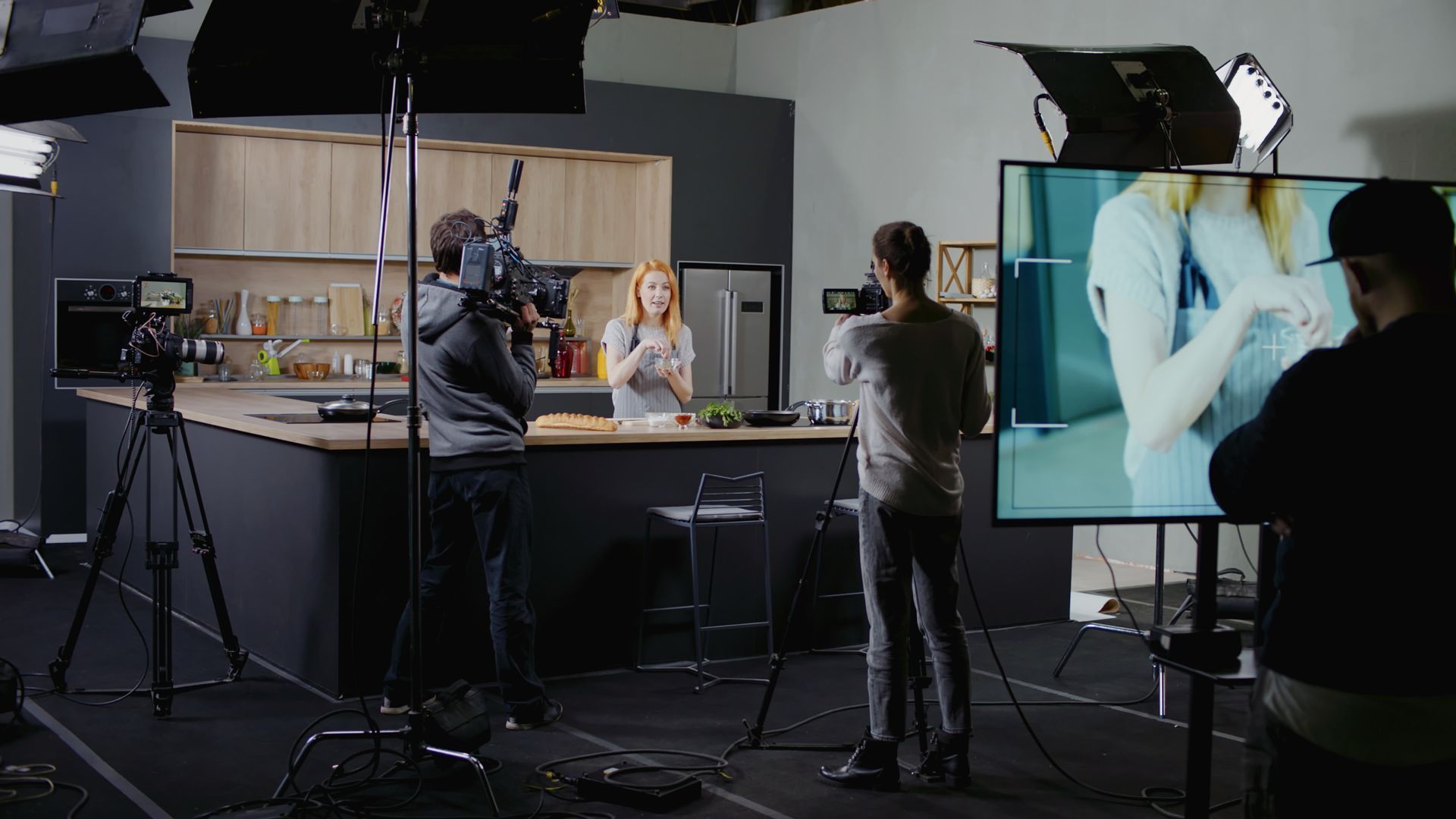 a group of people are standing in front of a television in a kitchen