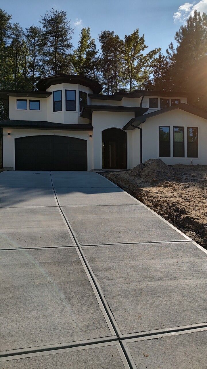 A large white house with a concrete driveway in front of it.