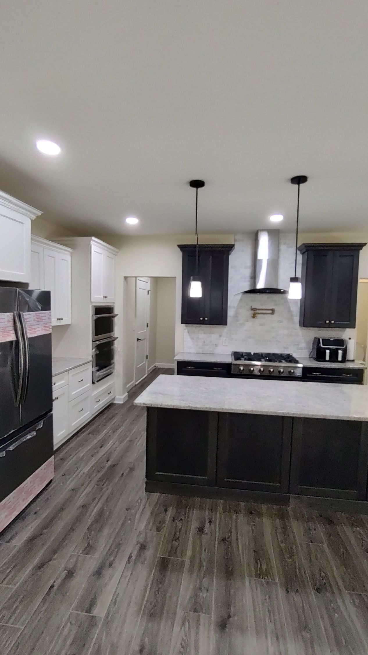 A kitchen with black cabinets , white cabinets , stainless steel appliances and a large island.