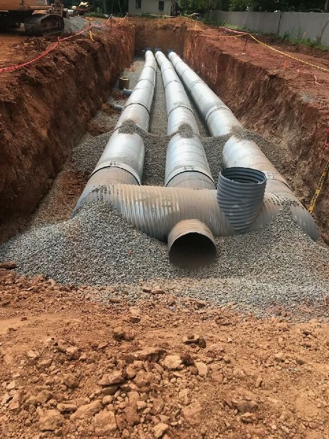 A row of pipes are being installed in a trench.