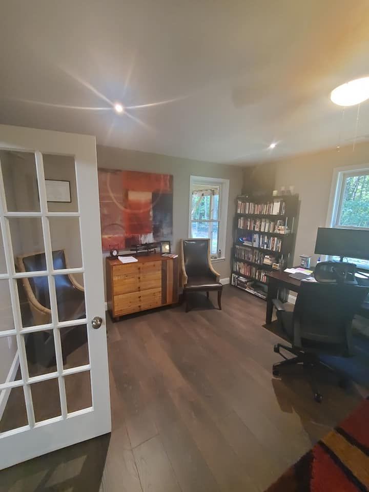 A living room with a desk and chairs and a french door.