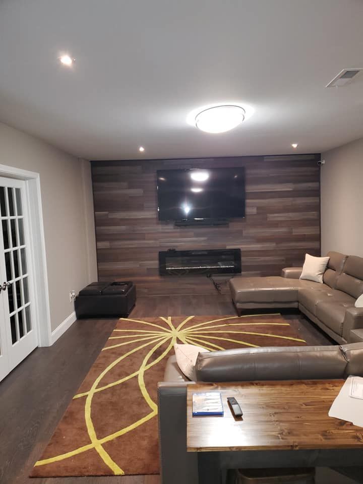 A living room with a couch and a flat screen tv on the wall.