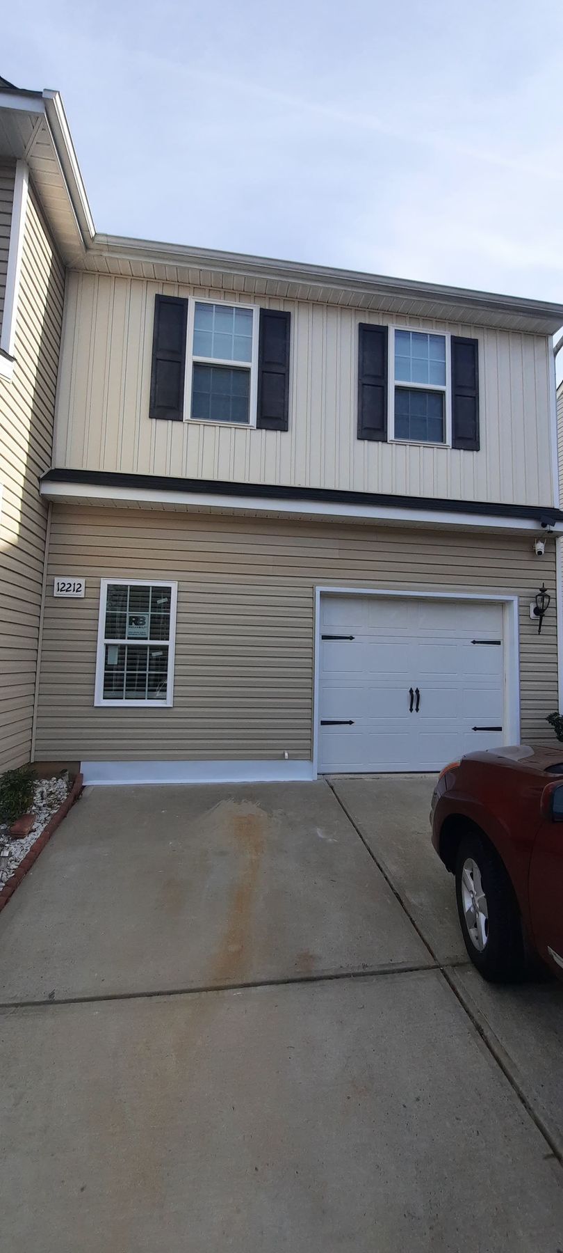 A car is parked in front of a house with a garage.