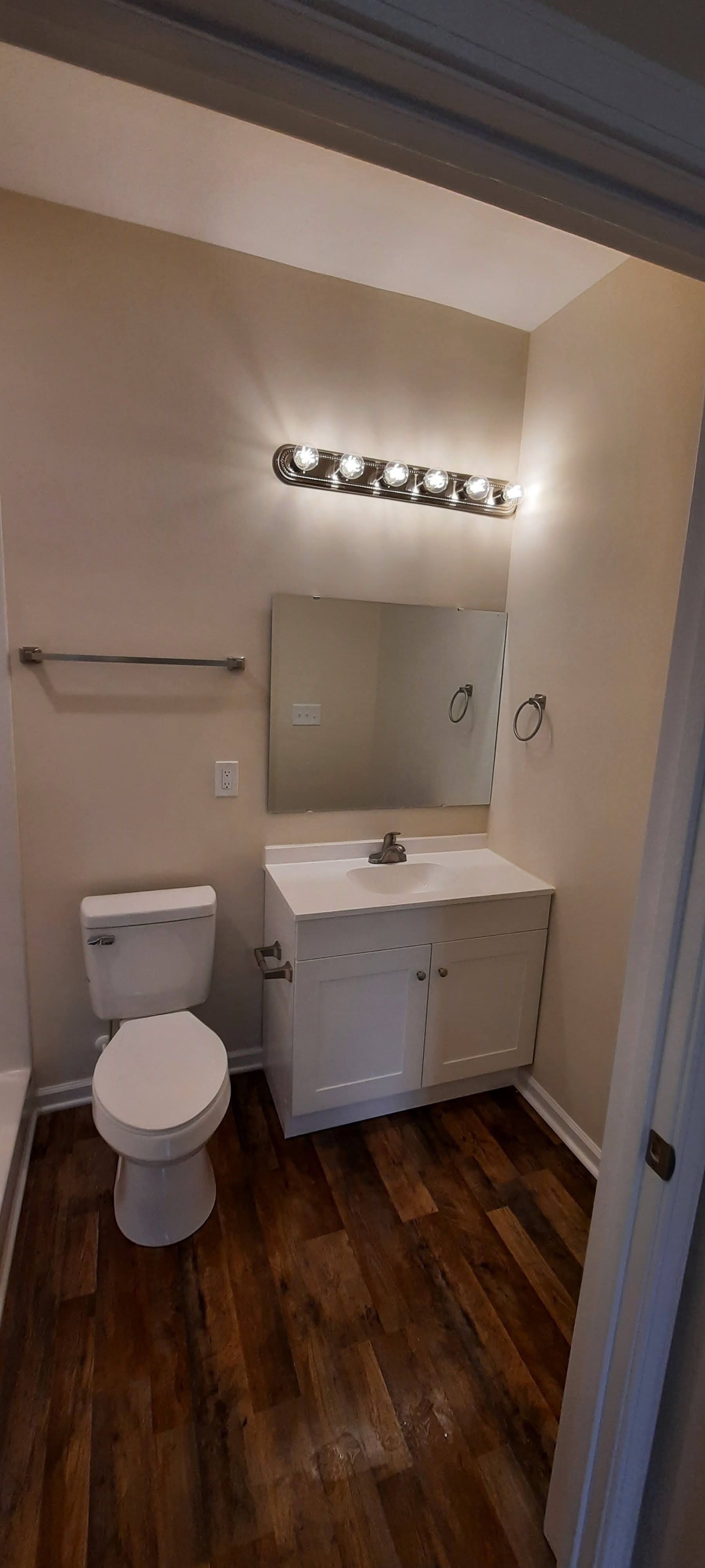 A bathroom with a toilet , sink and mirror.