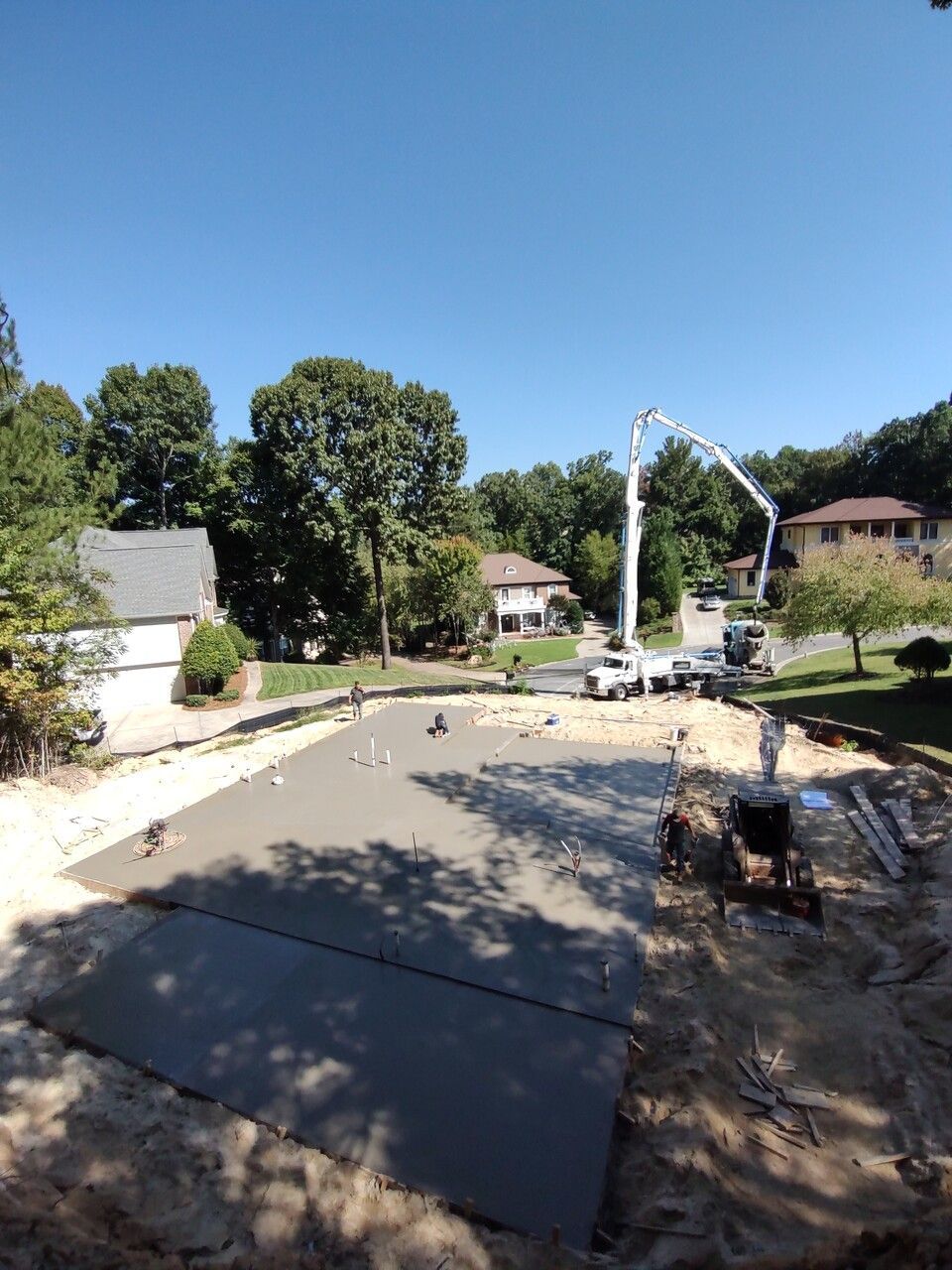 A concrete pump is being used to pour concrete into a driveway.