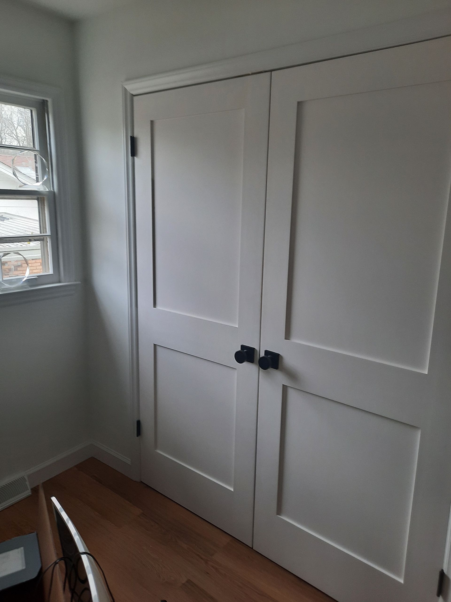 A room with two white doors and a window.