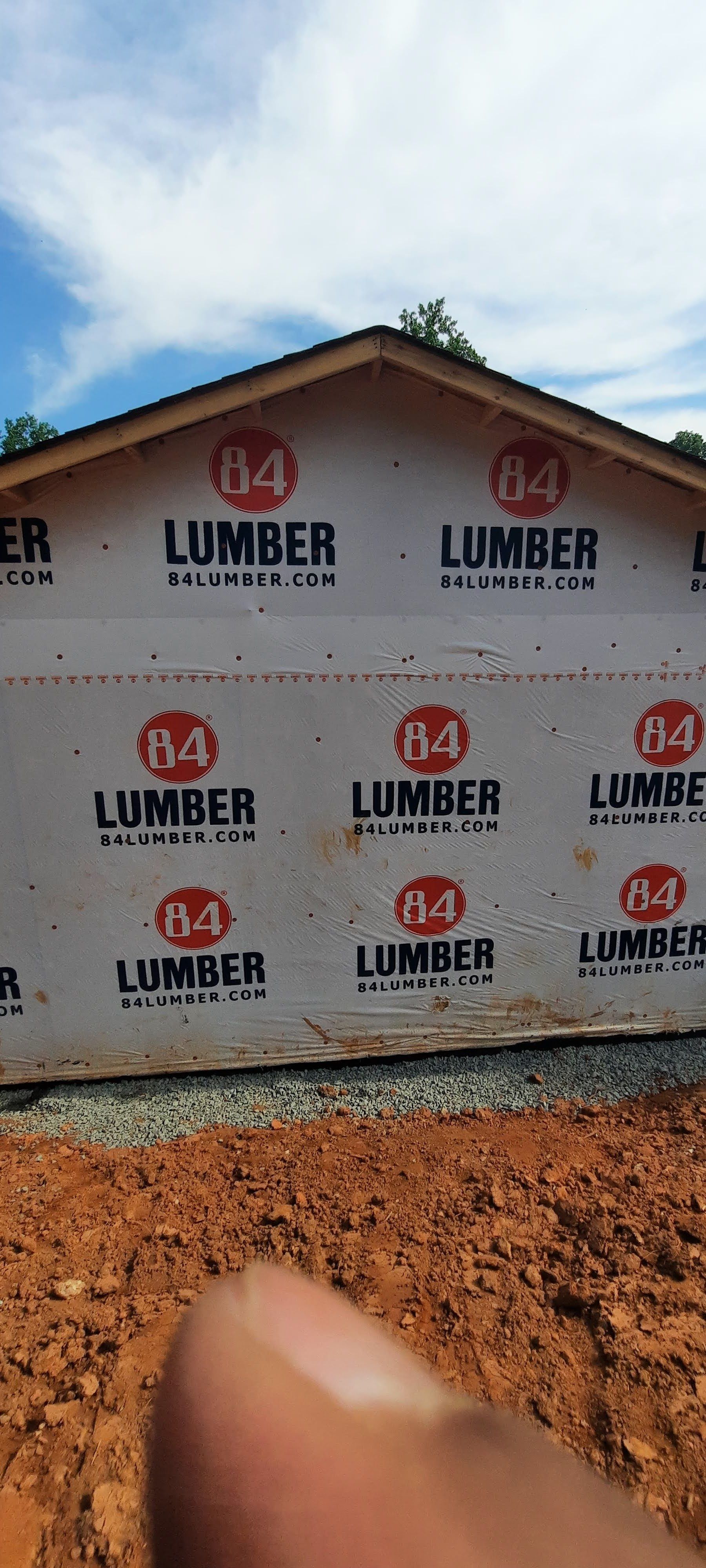 A person is holding a piece of lumber on the side of a building.