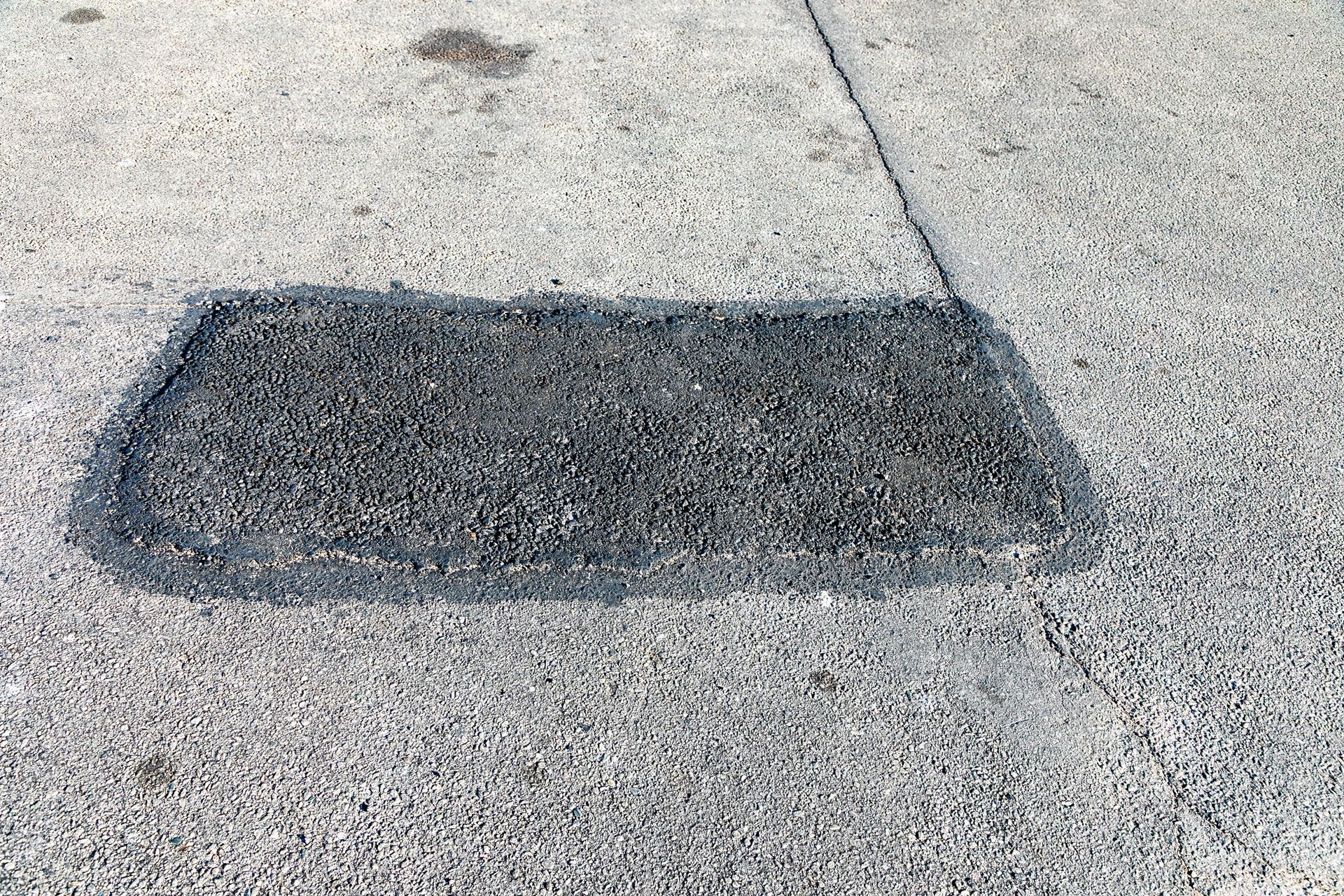 Asphalt patch on a concrete surface.