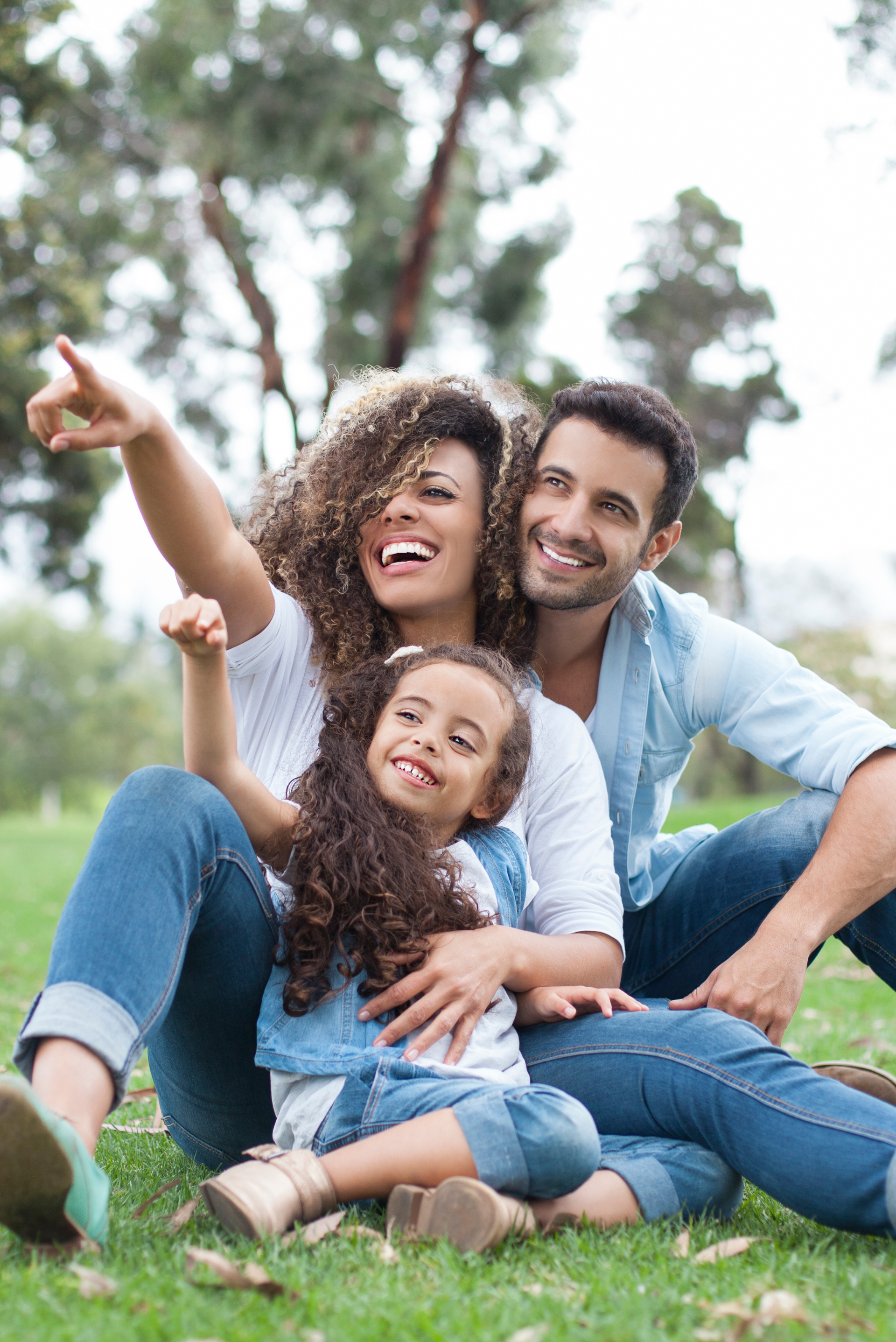 A family is sitting on the grass in a park.