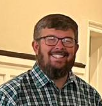 A man with a beard and glasses is smiling for the camera.