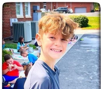 A young boy is smiling in front of a group of children