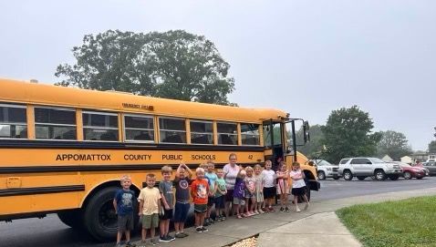 A group of children are standing in front of a school bus.
