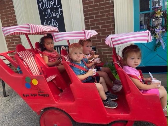 A group of children are sitting in a red buggy
