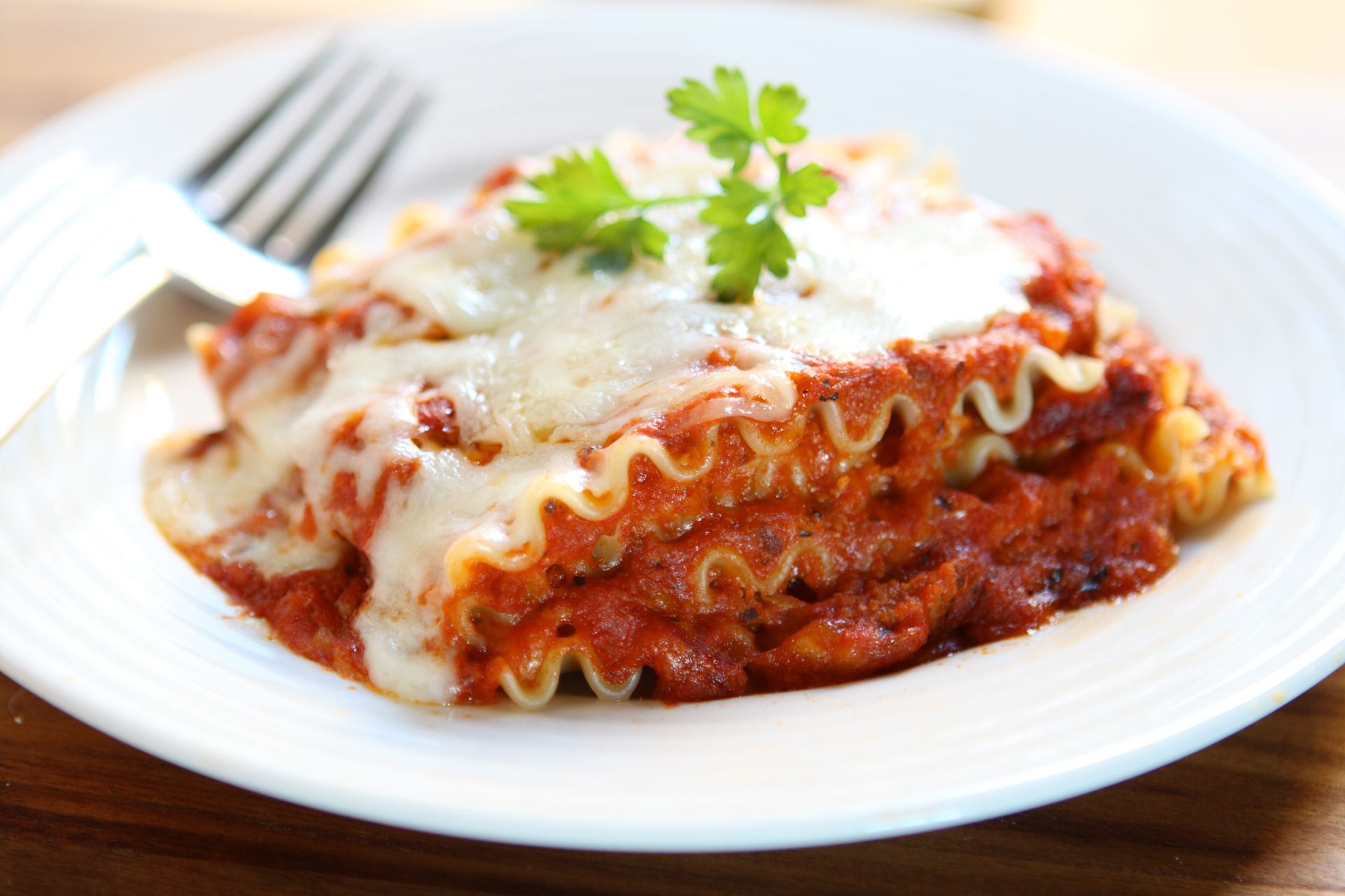 a slice of lasagna on a white plate with a fork