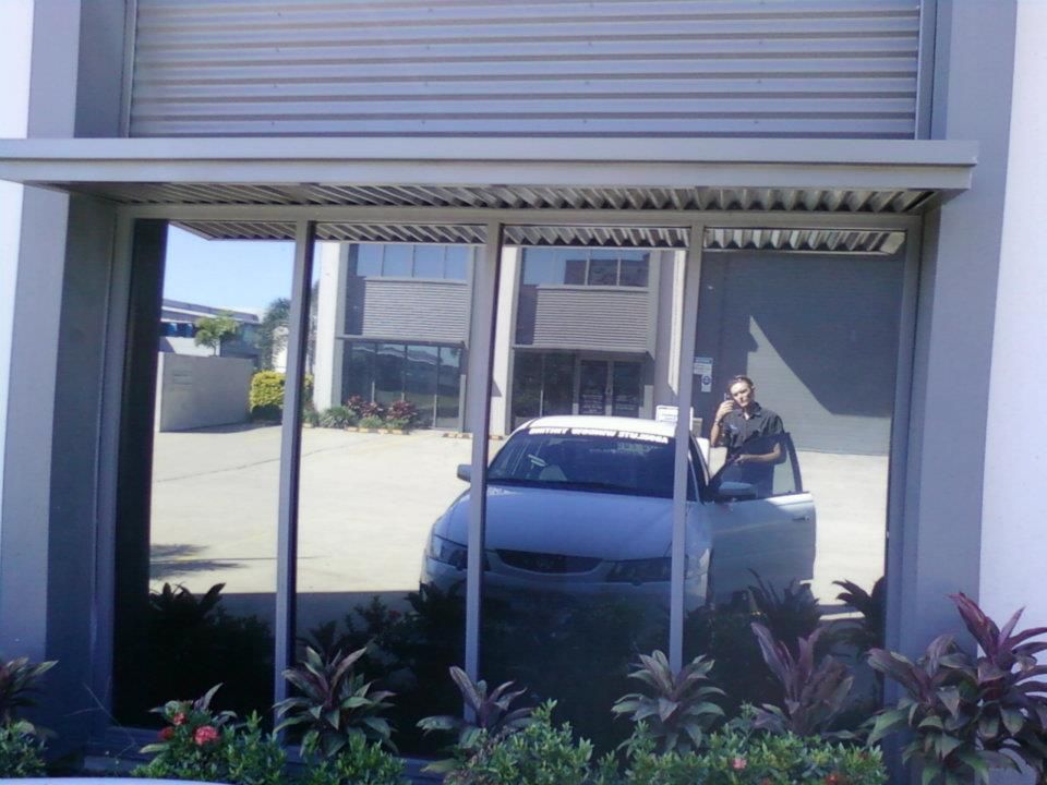 A White Car Is Parked in Front of A Building — Epic Window Tinting in Glenella, QLD