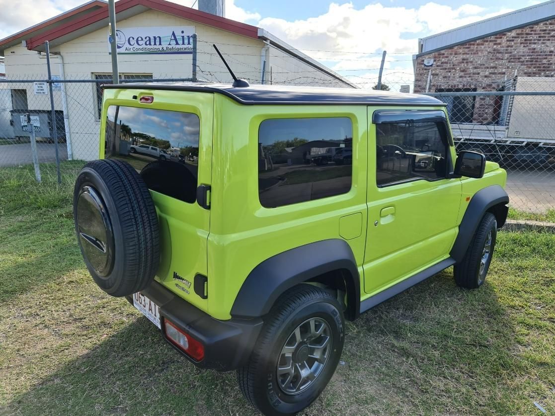 A Green Suzuki Jimny Is Parked in Front of A Building — Epic Window Tinting in Glenella, QLD