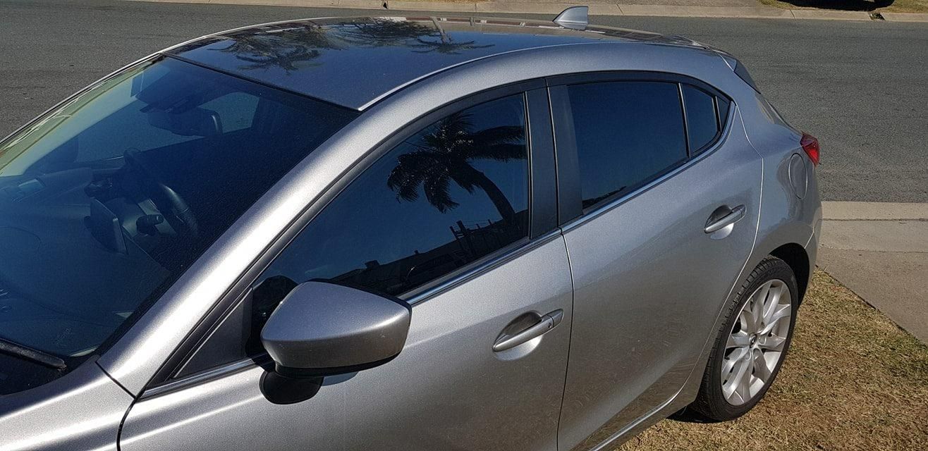 A Silver Car Is Parked on The Side of The Road — Epic Window Tinting in Glenella, QLD