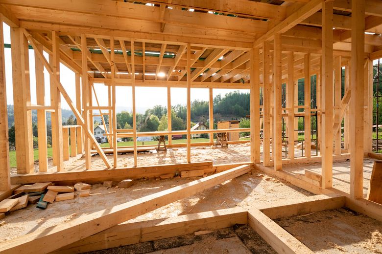 Wooden frame of a house under construction; open to a sunny outdoor view.