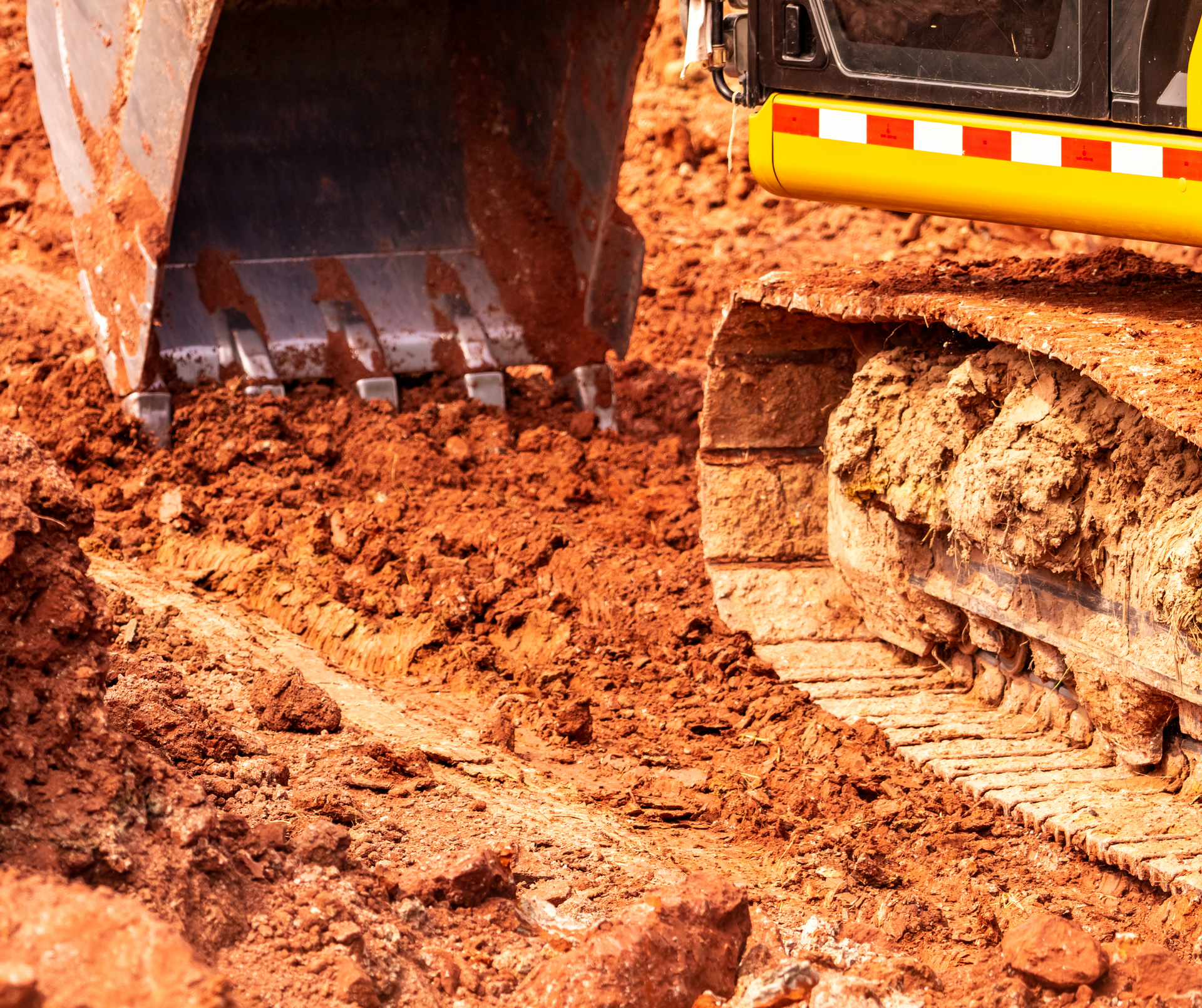 Excavator bucket and tracks working in a muddy construction site