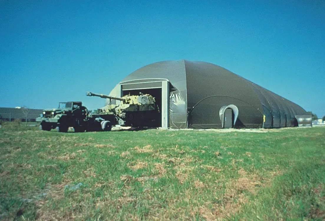 Two military vehicles are parked in front of a large building.