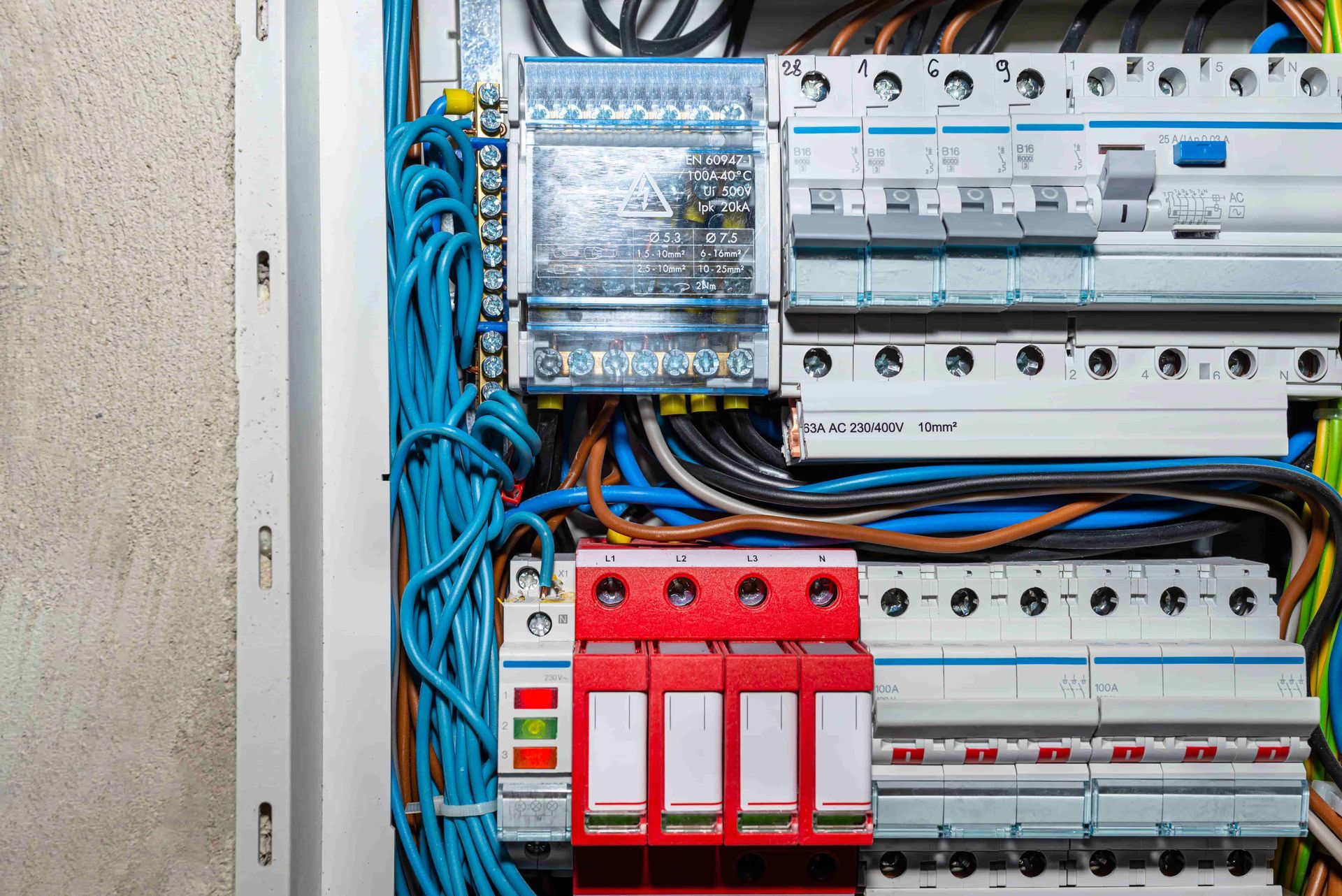 Electrical breaker panel with rows of switches and blue wiring inside a utility box