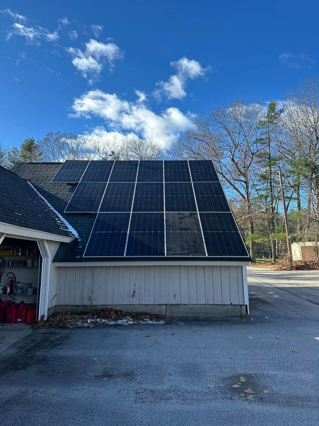 Solar panels mounted on a small building roof under a bright blue sky with scattered clouds.