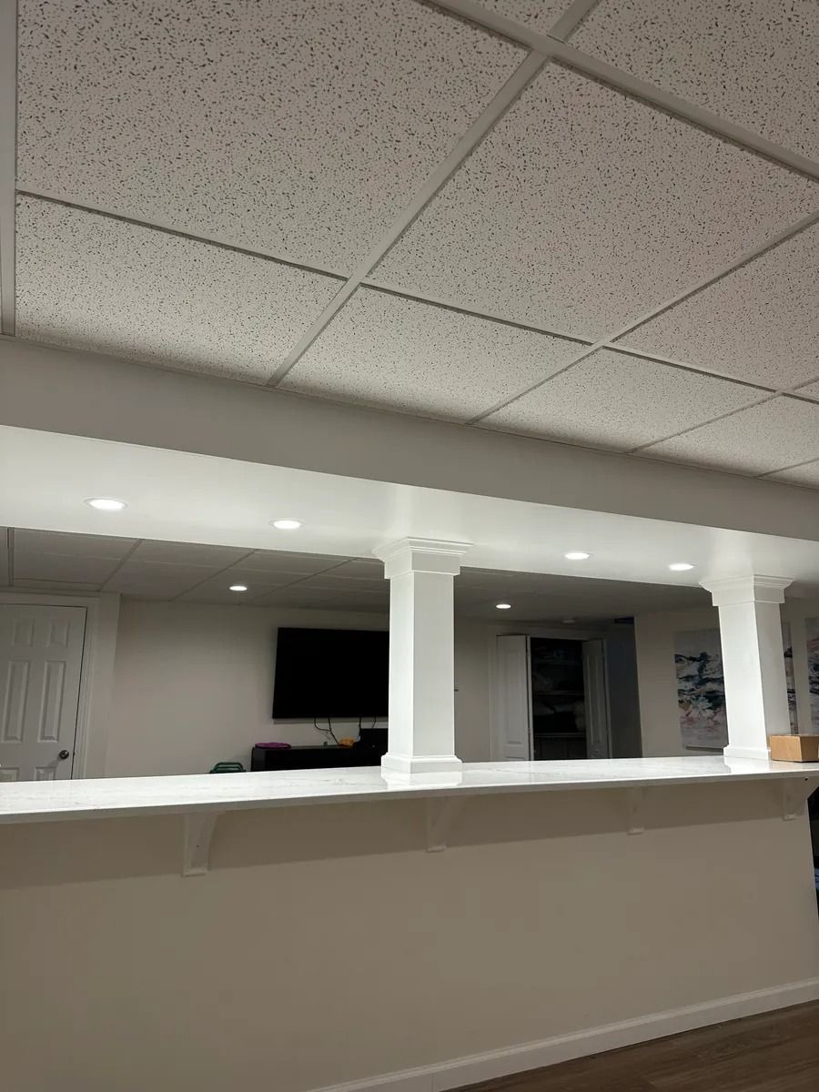 Empty office reception area with white columns, beige counter, and drop ceiling.
