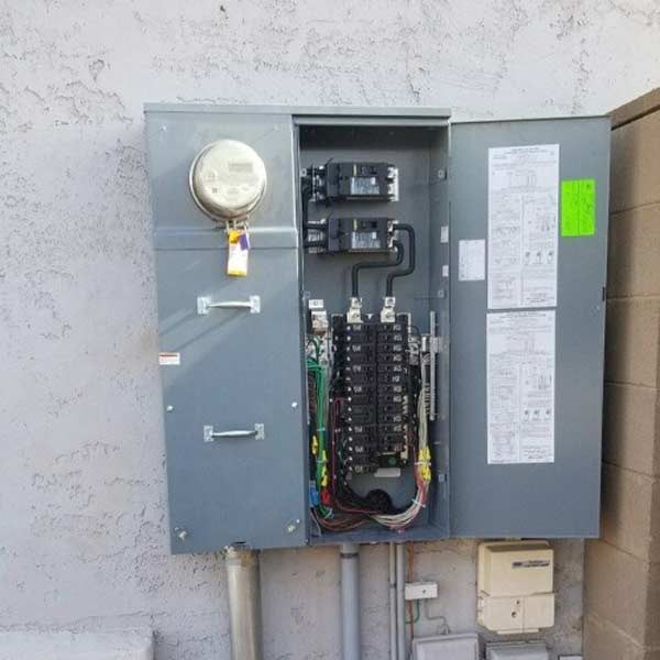 Open electrical service panel with meter and wiring mounted on an exterior wall
