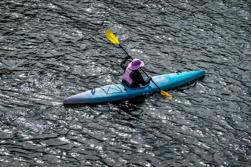 Kayaker in a blue kayak paddling across rippling water