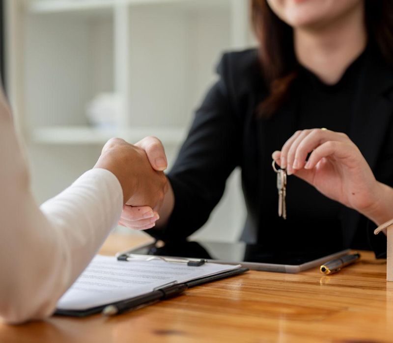 Handing over house keys across a table during a real estate meeting