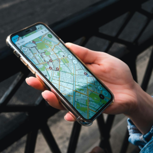 Hands holding a smartphone displaying a map/navigation app outdoors