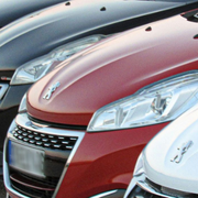 Row of parked cars, including red, black, and white vehicles, viewed from the front