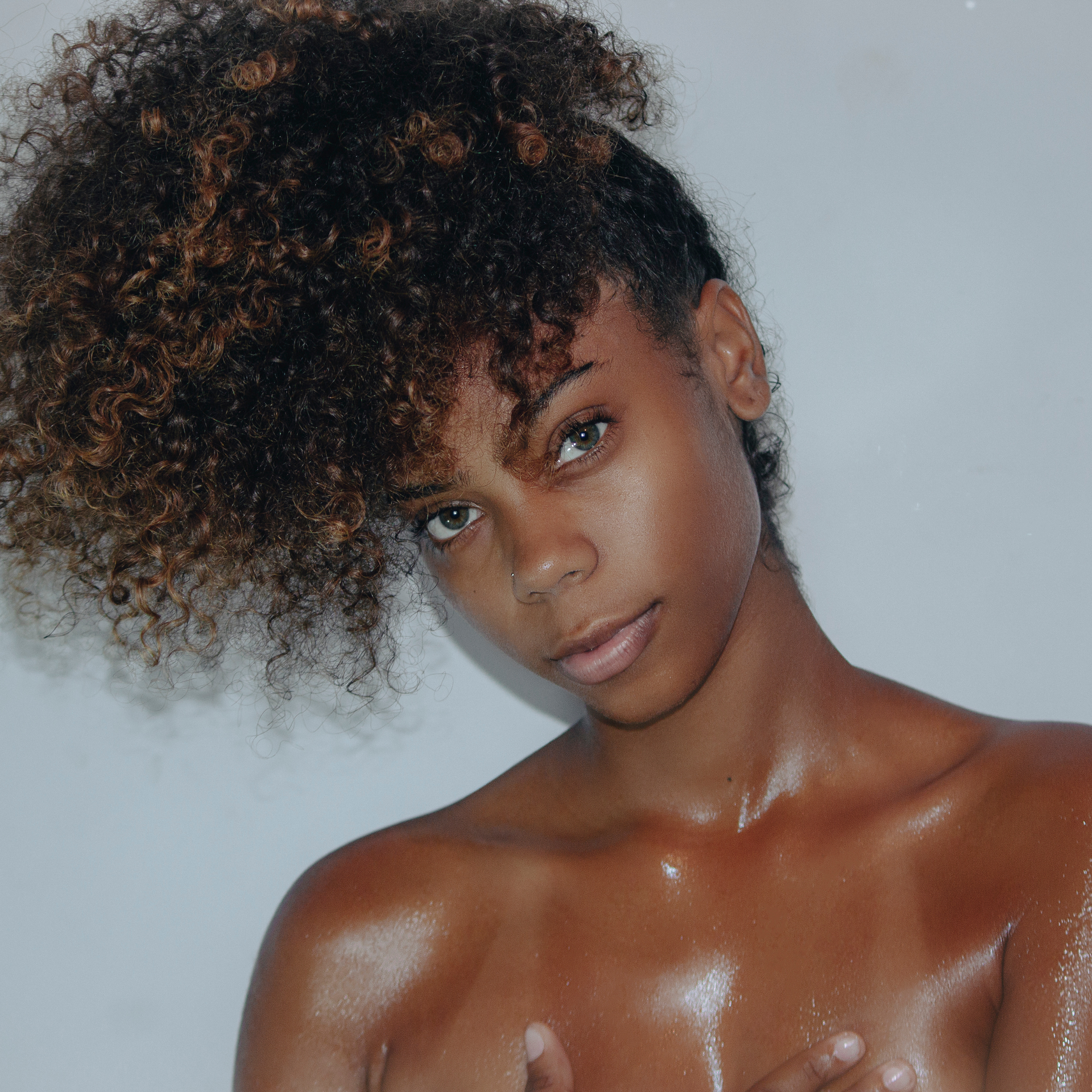 A woman with curly hair and a ponytail looks at the camera