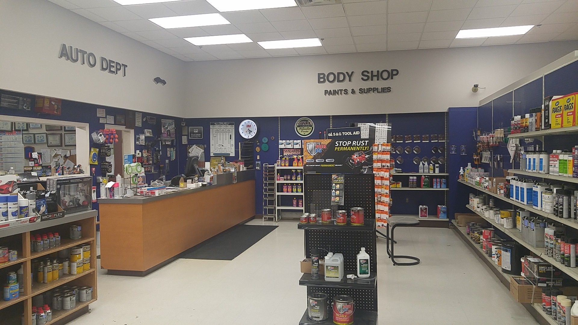 Auto parts store interior with shelves of products, a service counter, and “Body Shop” sign in back.