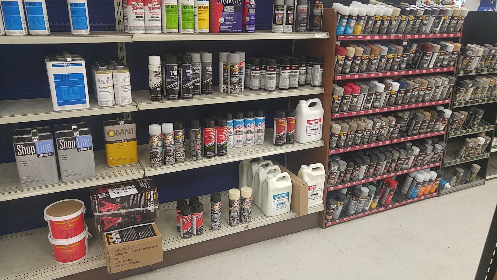Hardware store aisle with shelves of spray paint, cans, and painting supplies