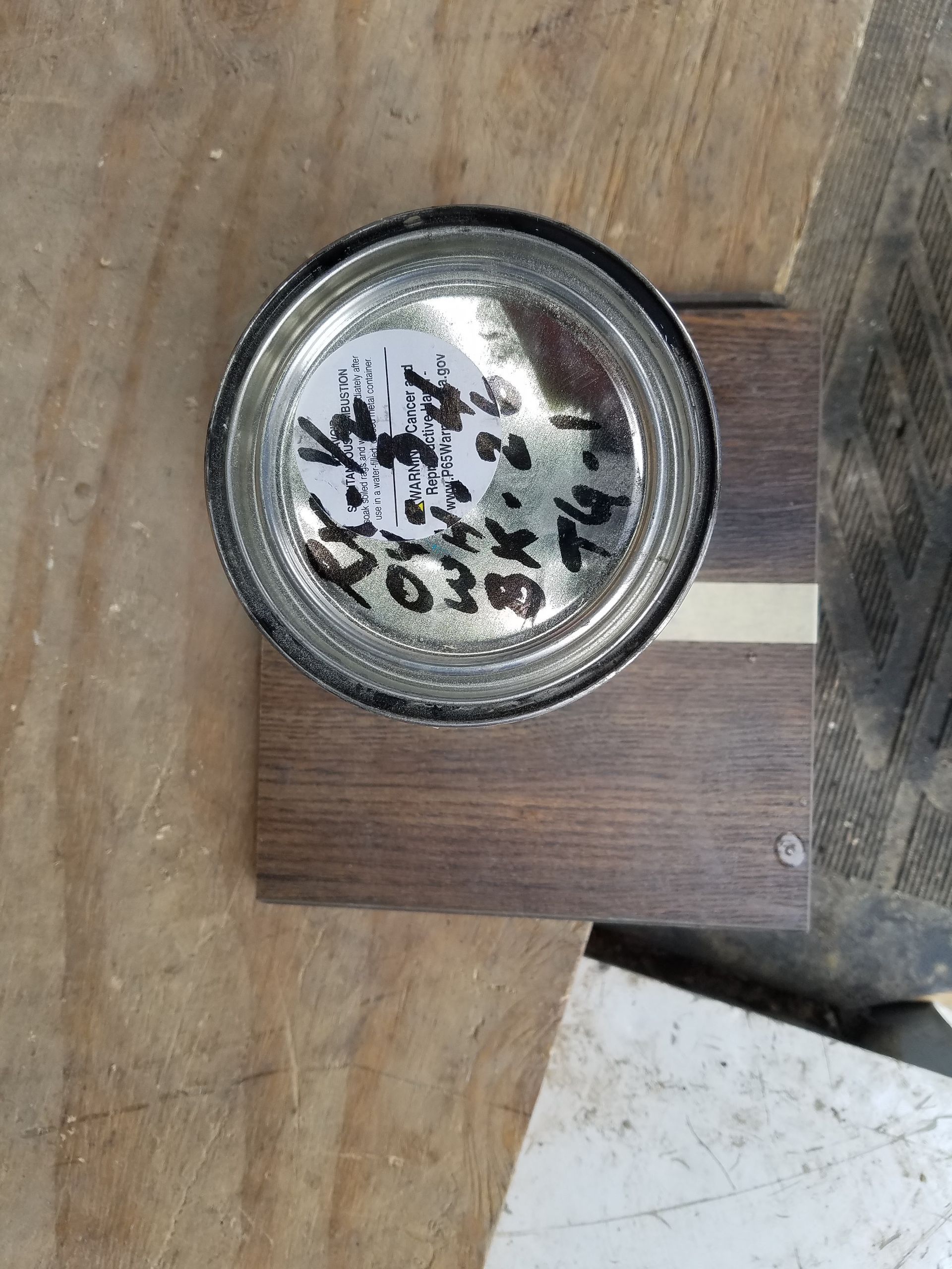 Round metal cap with black markings mounted on a wooden surface