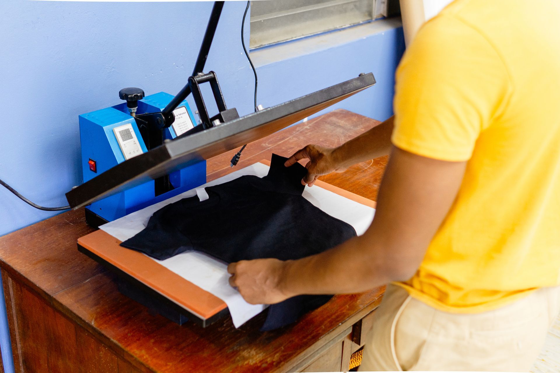 A close-up of a person’s arms working on an iron sublimation.