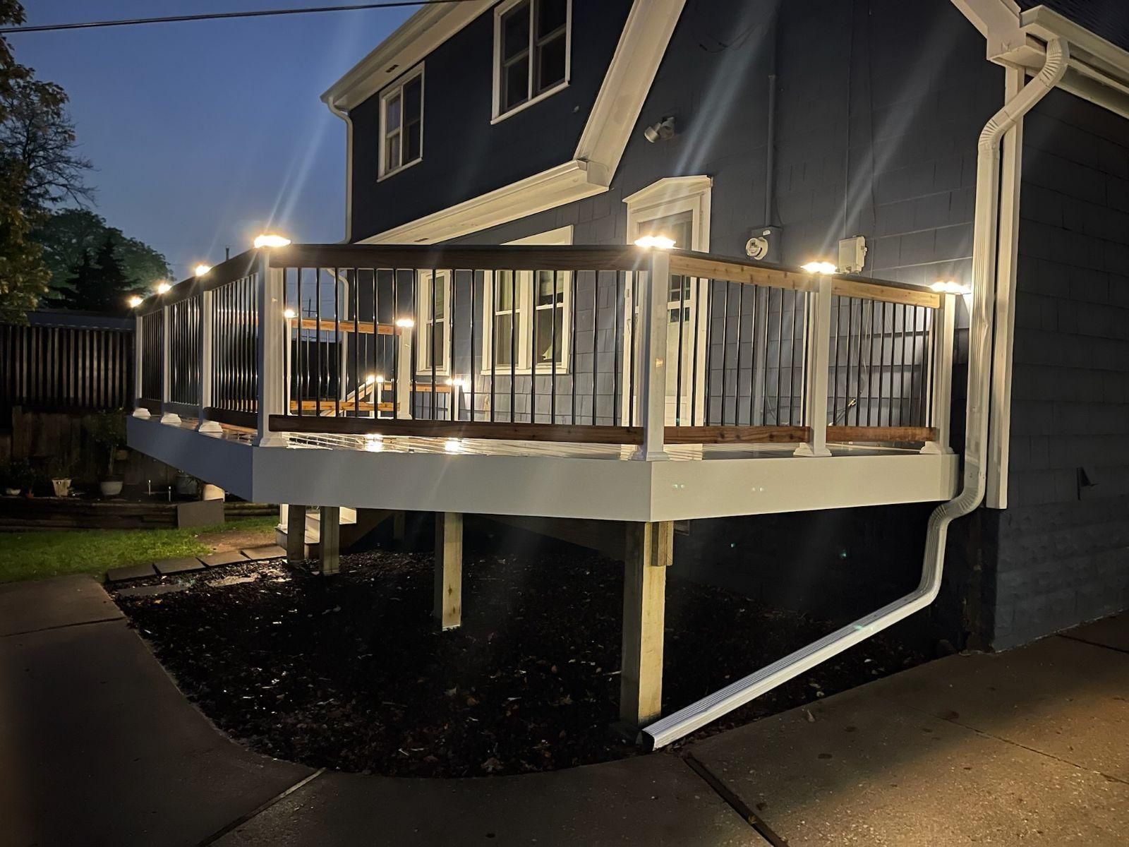 House exterior with a white-railed wooden deck and string lights at dusk