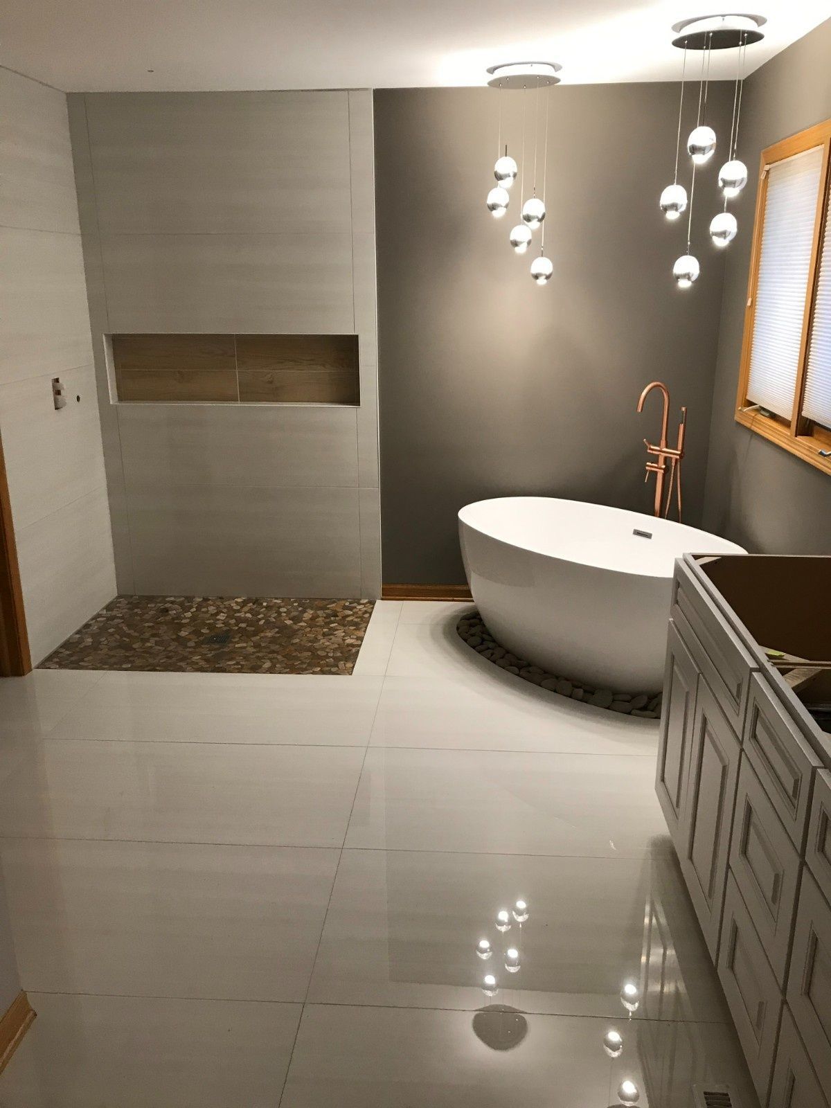 Modern bathroom with white tile, a freestanding tub, pendant lights, and a built-in shelf nook.